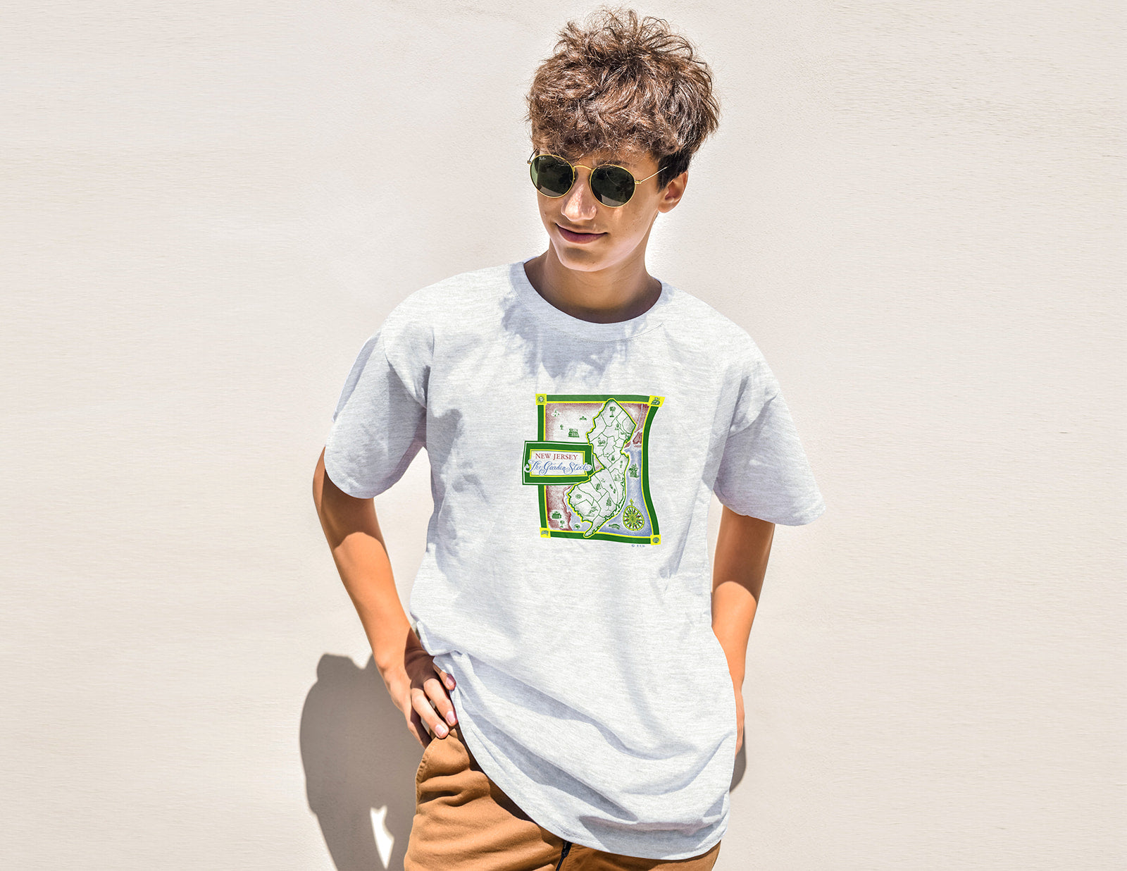 Person wearing a white t-shirt with a green and red logo on a plain background
