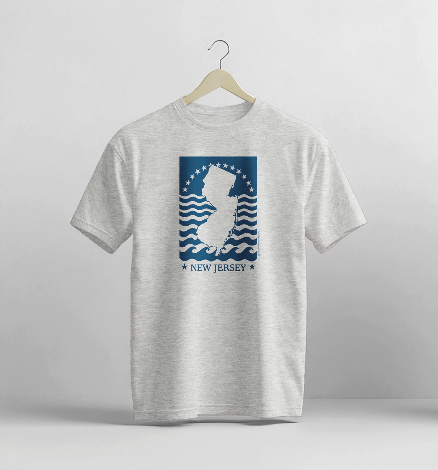 Gray t-shirt with New Jersey graphic on a hanger against a light gray background