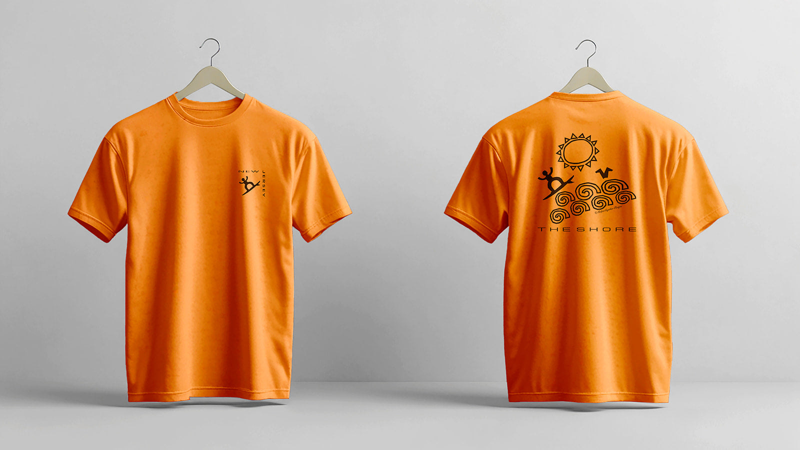 Orange t-shirt with a design on the front and back on hangers against a gray background