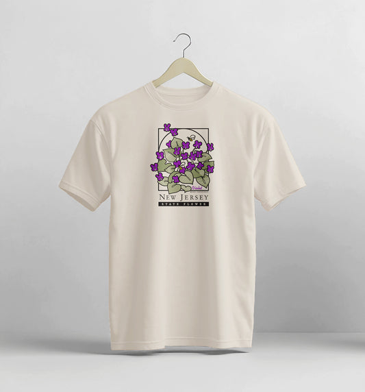 Beige t-shirt with a graphic design of purple flowers on a hanger against a light gray background