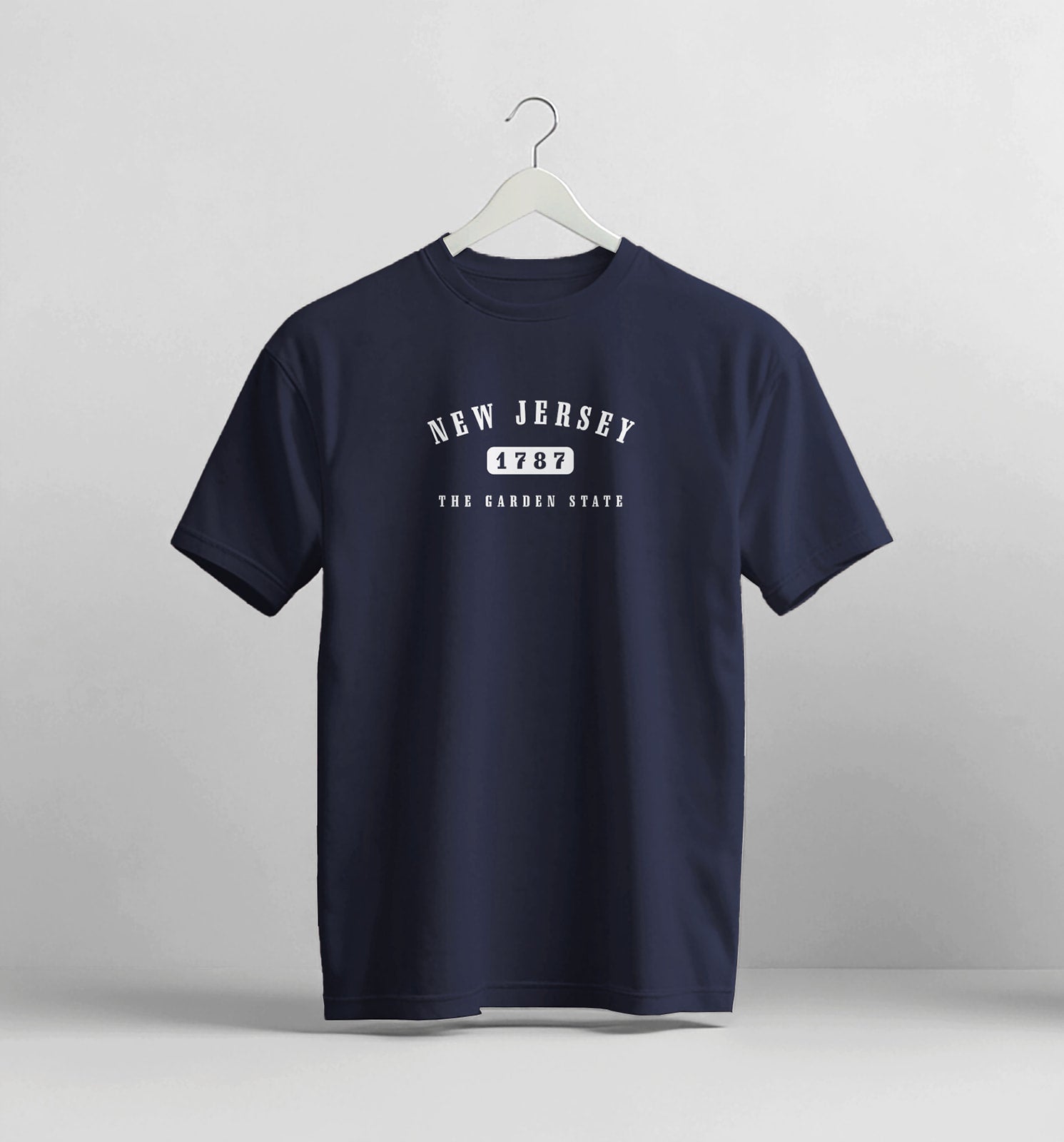 Navy blue t-shirt with 'New Jersey' design on a hanger against a light gray background