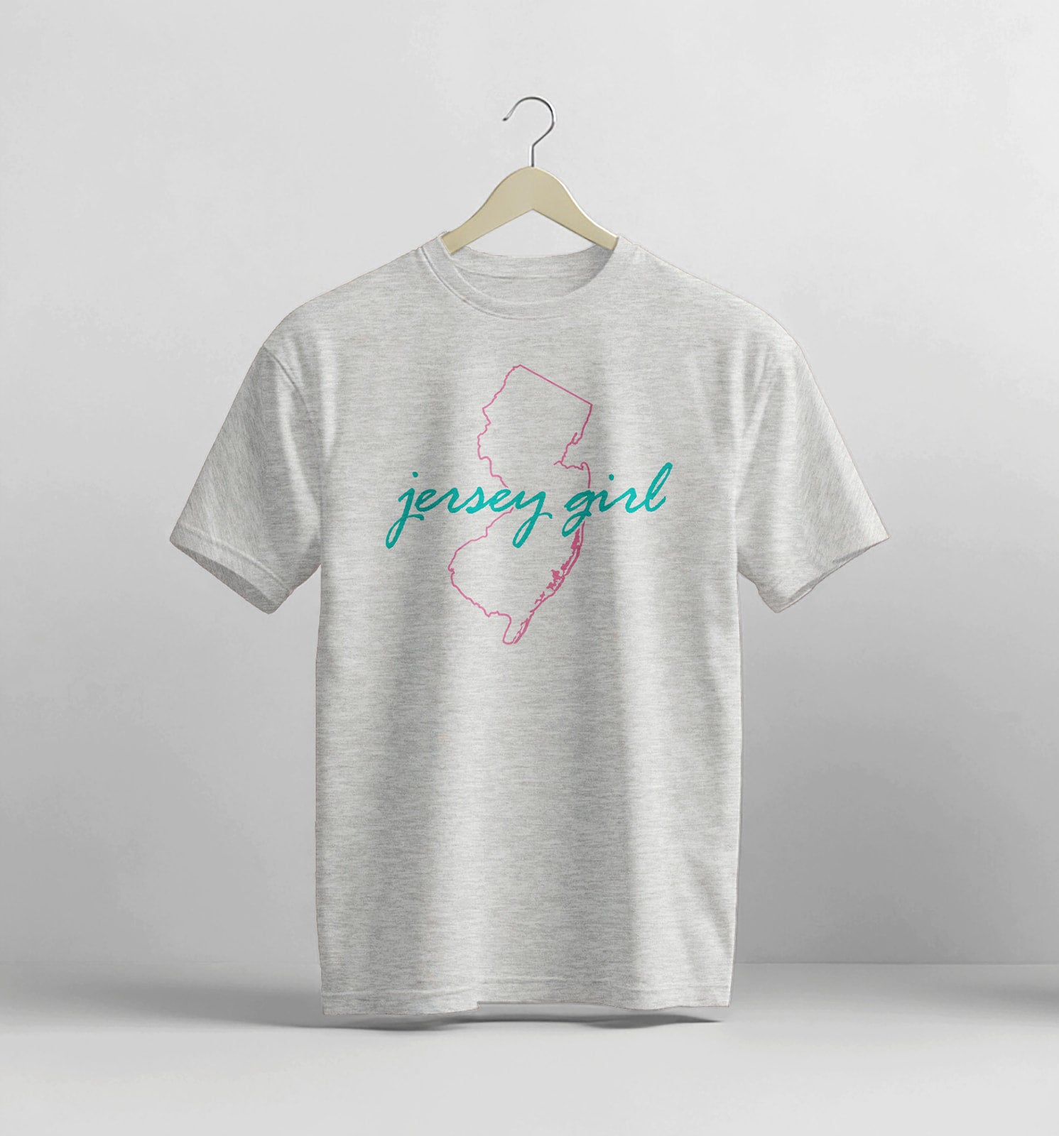 Gray t-shirt with 'jersey girl' design on a hanger against a light gray background