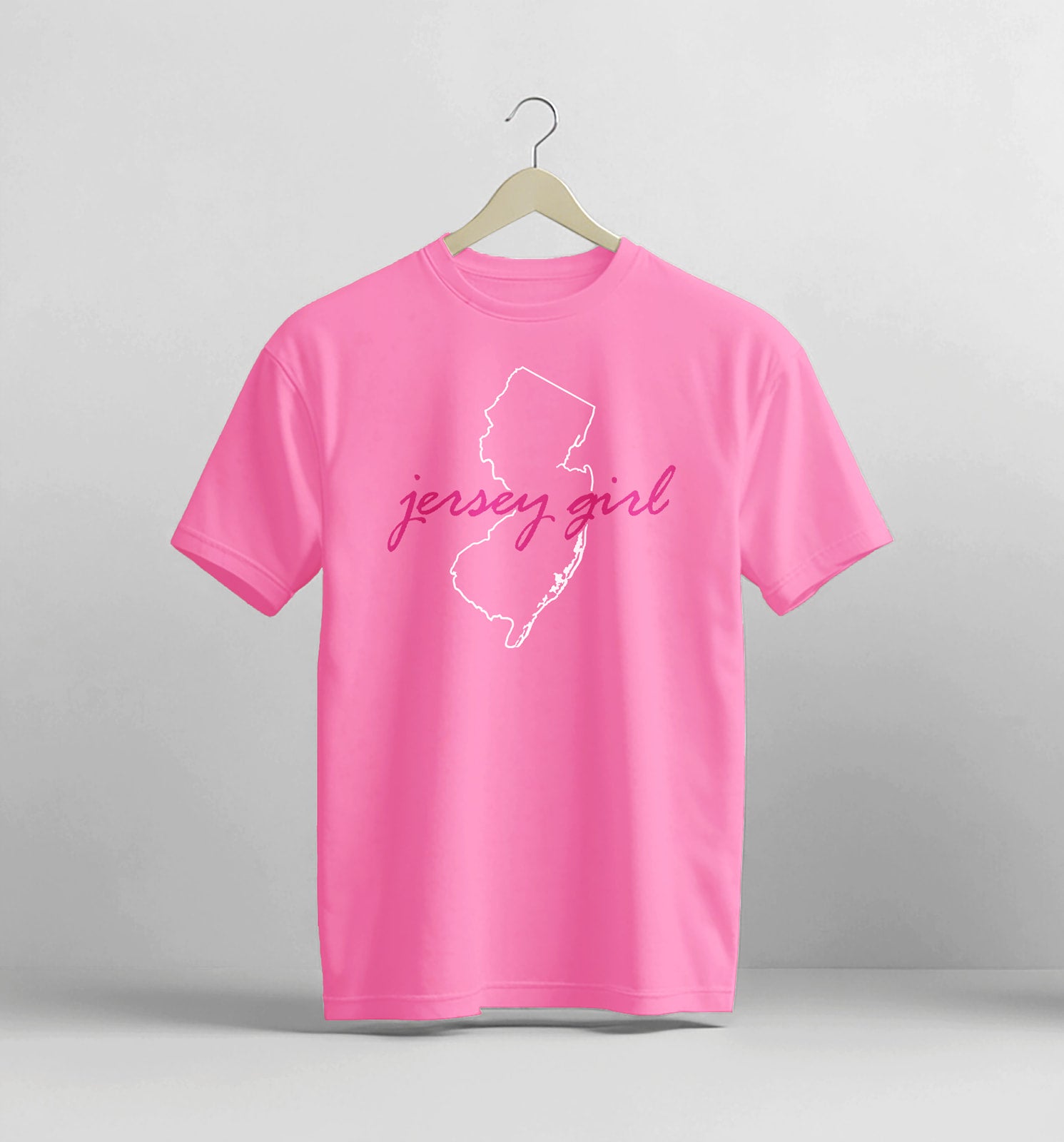 Pink t-shirt with 'jersey girl' text and outline on a hanger against a gray background