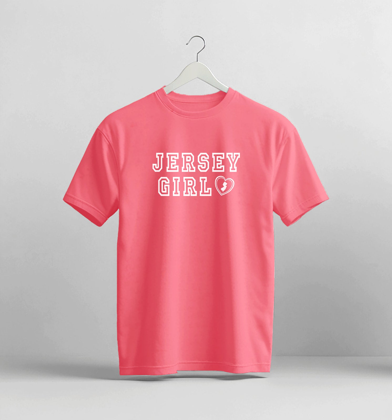 Pink t-shirt with 'Jersey Girl' text on a hanger against a gray background