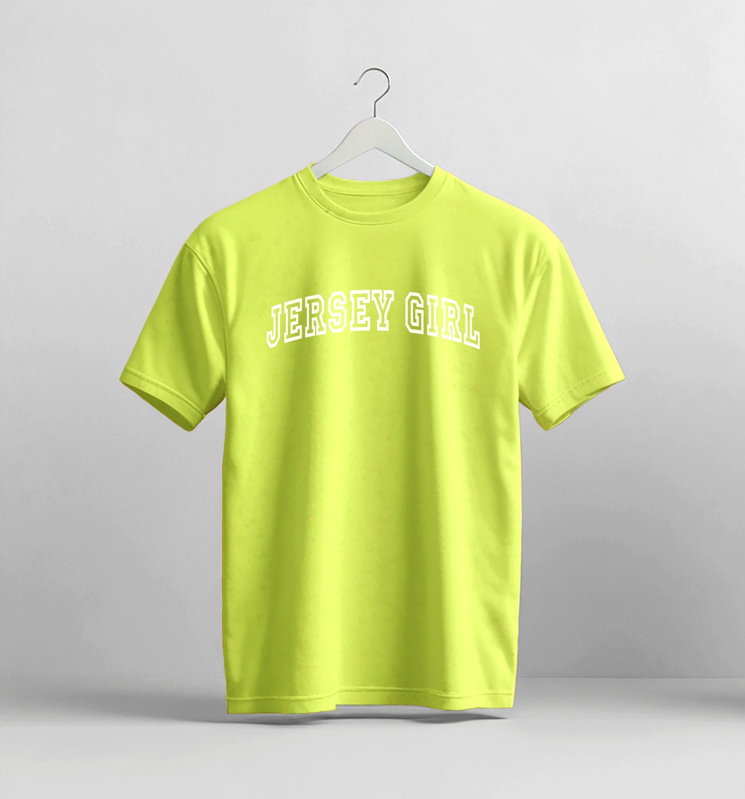 Yellow t-shirt with 'Jersey Girl' text on a hanger against a gray background