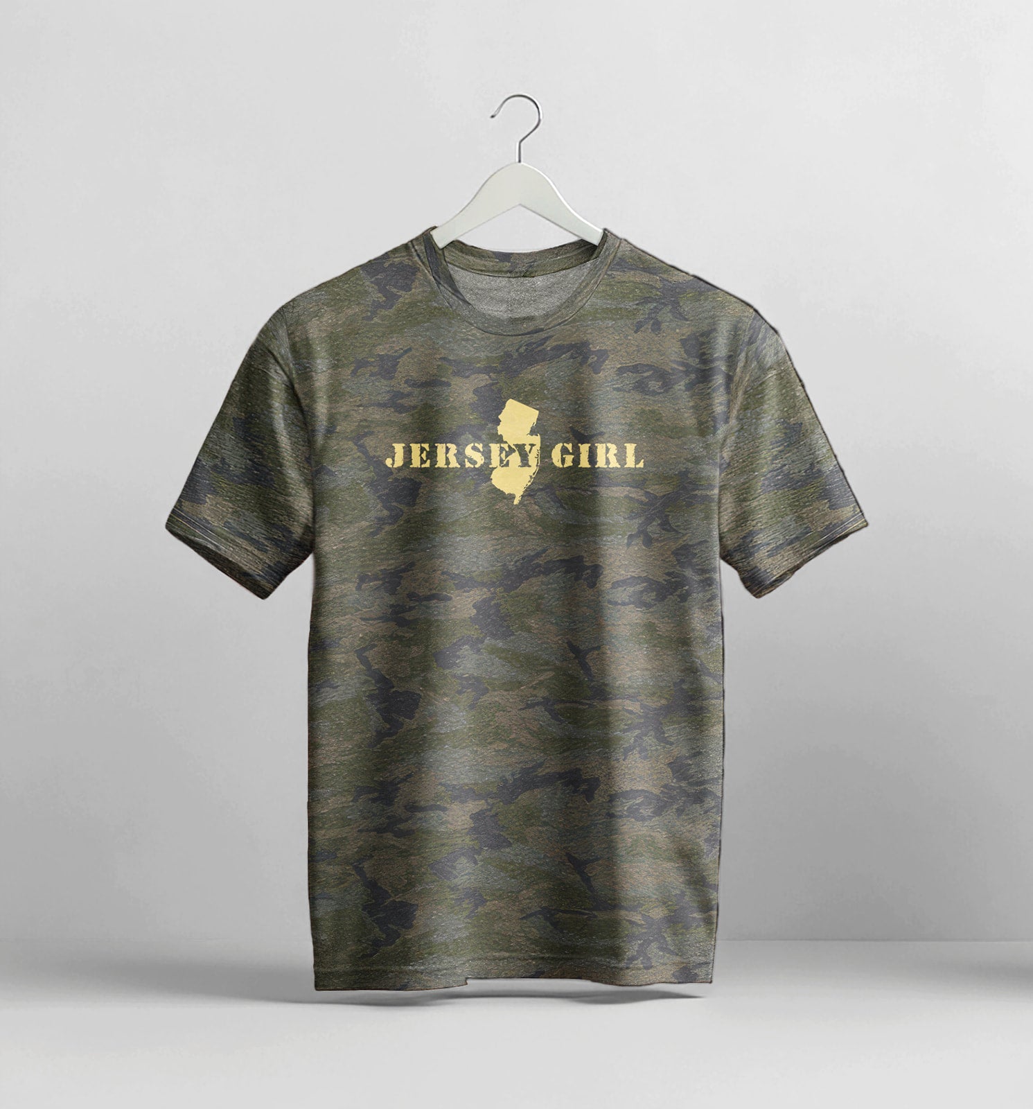 Camouflage t-shirt with 'Jersey Girl' text on a hanger against a gray background